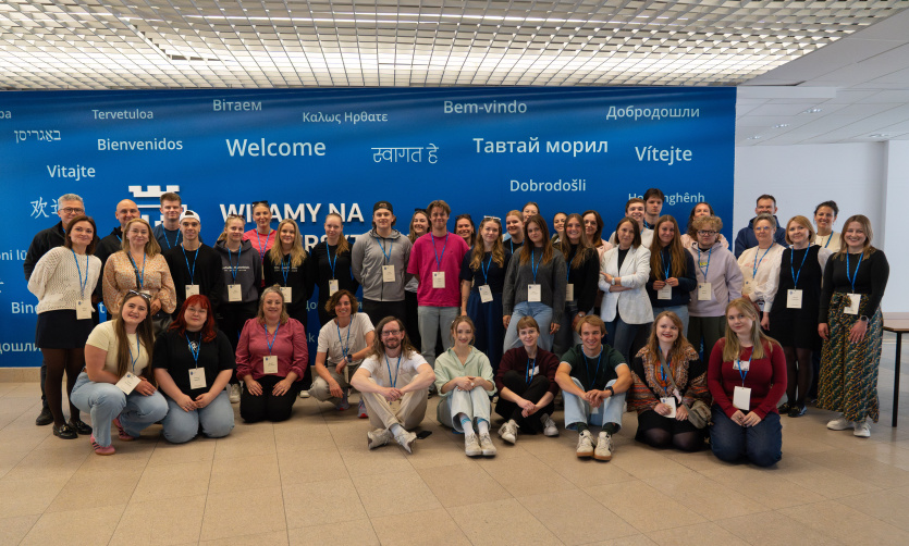 Uczestniczki i uczestnicy BIP „Outdoor Education in Intercultural Perspective” na tle ściany "Witamy na UG"