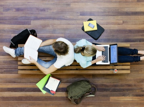 Na zdjęciu dwoje uczniów z laptopem i książkami w ręku