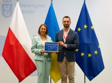 prof. Ewa Szymczak i Wołodymyr Szejko z cerytfikatem członkowstwa w GCUS; w tle flagi Polski, Ukrainy i UE