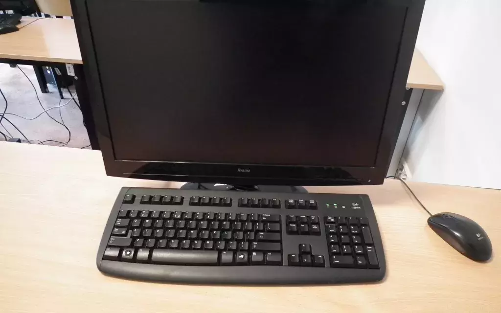 widok jednego z przykładowych zestawów komputerowych przy stanowisku. komputer stacjonarny, ekran, myszka