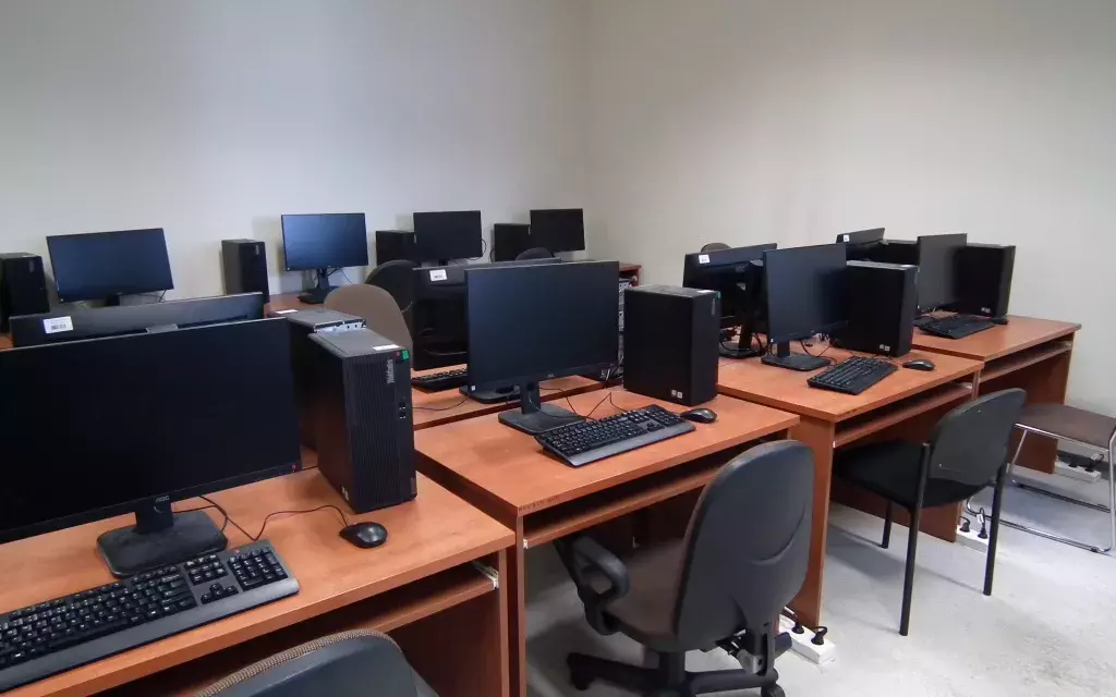 widok jednej z przykładowych pracowni komputerowych wydziału. wyraźnie widać ustawienie krzeseł, ławek szkolnych oraz zestawy komputerowe