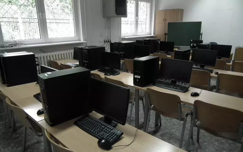 widok jednej z przykładowych pracowni komputerowych wydziału. wyraźnie widać ustawienie krzeseł, ławek szkolnych oraz zestawy komputerowe