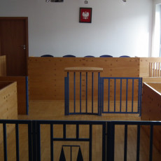 widok jednej z sal rozpraw z tyłu w kierunku bramek, ław dla przysięgłych oraz stołu sędziowskiego