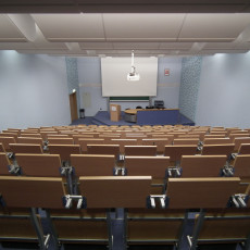 widok z góry - pokazujący kaskadowy układ siedzisk i pulpitów dla słuchaczy. na dalszym planie podest ze stołem prezydialnym oraz mównicą
