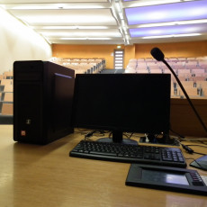 widok wyposażenia multimedialnego na biurku prowadzącego : komputer stacjonarny , ekran, mikrofon