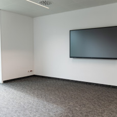 Jedna część sali konferencyjnej, telewizor na ścianie.
